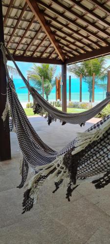 a hammock on a beach with the ocean in the background at Flat Tabatinga Nord, vista para o mar in Conde