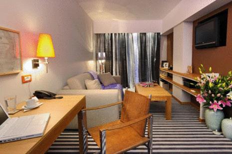 a living room with a couch and a desk in a room at Galaxy City Center Hotel in Patra