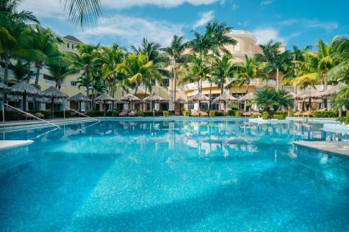 a swimming pool at a resort with palm trees at JOIA Rose Hall by Iberostar - Adults Only All Inclusive Resort in Montego Bay