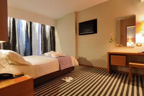 a hotel room with a bed and a desk at Galaxy City Center Hotel in Patra