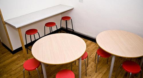 斯特雷特利的住宿－泰晤士YHA斯特雷特利酒店，教室里一组桌子和红色凳子