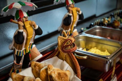 two toy figurines standing next to a counter with food at Hotel Hacienda Plaza de Armas in Puno