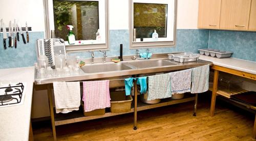 a kitchen with a sink and two windows and towels at YHA Streatley on Thames in Streatley