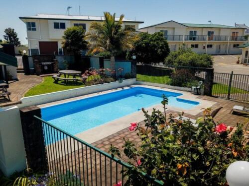 a swimming pool in the middle of a yard at Cottage Park Thermal Motel in Tauranga