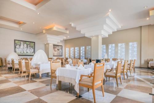 a dining room with white tables and chairs at JOIA Rose Hall by Iberostar - Adults Only All Inclusive Resort in Montego Bay