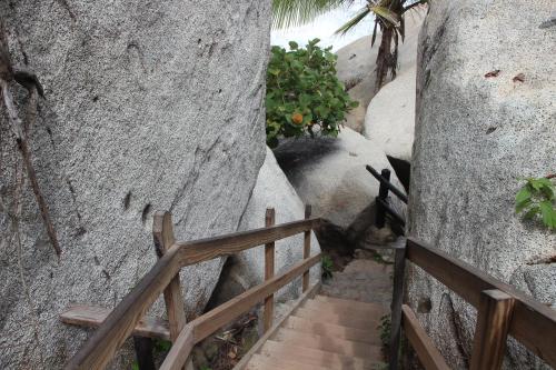 a staircase leading up to a rock wall with a wooden fence at HOSTAL MIRADOR dentro del parque tayrona in El Zaino