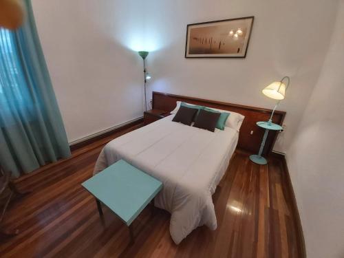 um pequeno quarto com uma cama e um candeeiro em GARDEN ROOMS em Castro-Urdiales