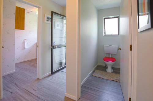 a bathroom with a toilet and a red stool at Sunny Warren in Wanaka in Wanaka
