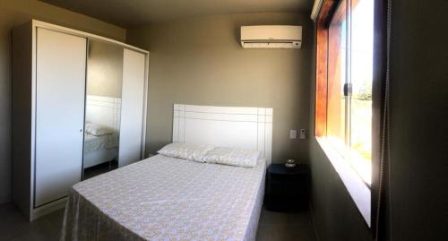 a small bedroom with a bed and a window at Apartamento Barra Grande Península de Marau Bahia in Marau