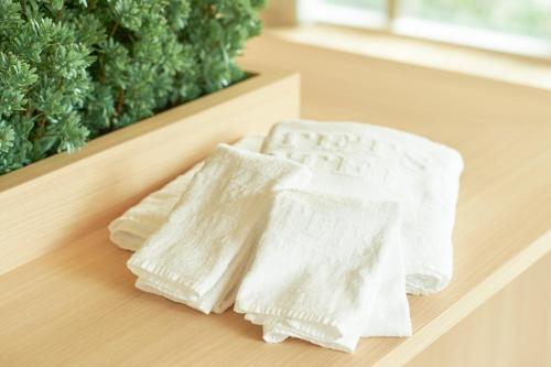 two white towels sitting on a wooden table at Sotetsu Fresa Inn Daimon in Tokyo