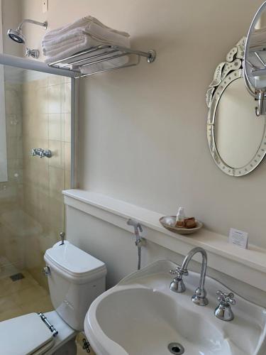 a bathroom with a toilet and a sink and a mirror at Hotel Boutique Inconfidentes in Tiradentes