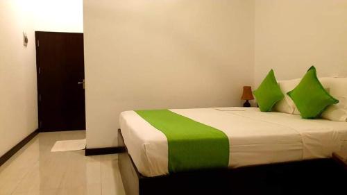 a bedroom with a large bed with green pillows at KITHULA Boutique Hotel in Hikkaduwa