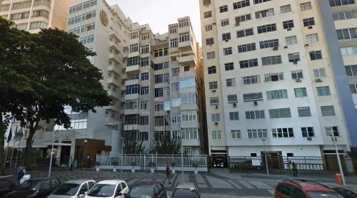 a parking lot with parked cars in front of buildings at Copacabana Beach, Av Atlântica in Rio de Janeiro