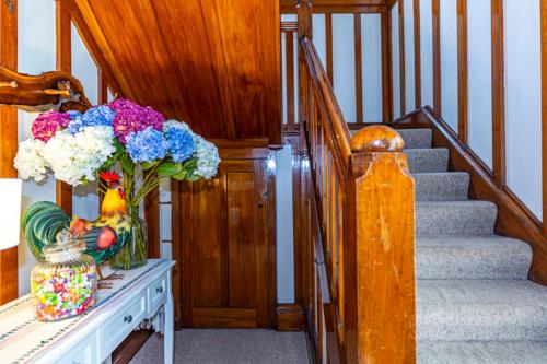 a staircase with a vase of flowers on a table at The Magnolia Villa CBD in Timaru