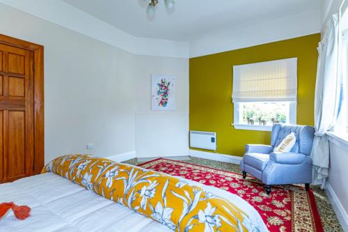 a bedroom with a bed and a chair and a window at The Magnolia Villa CBD in Timaru