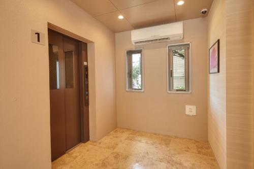 an empty hallway with a door and a window at New Normal Hotel in NAMINOUE ニューノーマルホテルイン波の上 in Naha