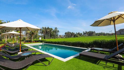 a swimming pool with chairs and umbrellas at Adil Villa & Resort in Ubud