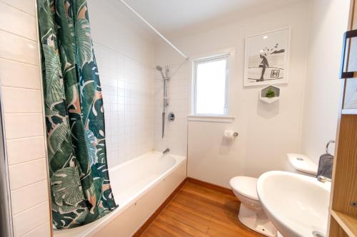 a bathroom with a tub and a toilet and a sink at The Coastal Casa ~ Close to the beach and town in Mount Maunganui