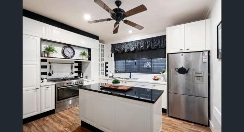 a kitchen with white cabinets and a ceiling fan at The Weeping Elm - Large and Spacious in Albury