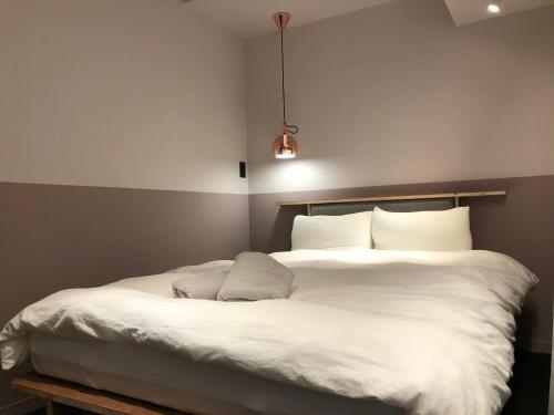 uma cama com lençóis brancos e almofadas num quarto em Hotel Asakusa KANNONURA em Tóquio