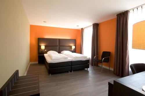 a bedroom with a bed with an orange wall at Hotel Roermond Next Door in Roermond