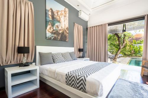 Un dormitorio con una cama y una ventana grande. en Jagaditha Villas, en Sanur