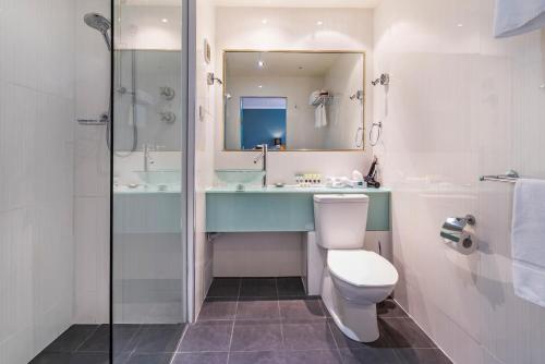 a bathroom with a toilet and a sink and a mirror at Nightelier Devonport Gateway Hotel in Devonport
