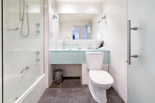 a bathroom with a toilet and a sink and a tub at Nightelier Devonport Gateway Hotel in Devonport