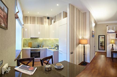 una cocina con armarios blancos y una mesa con sillas. en Apartment on Zagorodny avenue 22, en San Petersburgo