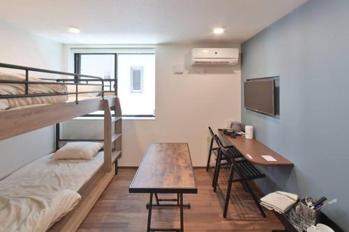 東京にあるStylewood Nishi-Shinjukuの机と二段ベッドのある寮の部屋