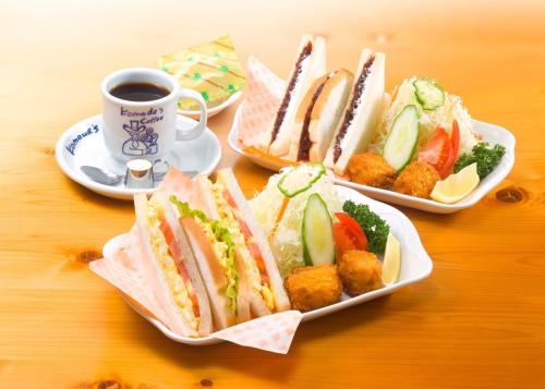 a table with two plates of sandwiches and a cup of coffee at Phoenix Ryukyu Henzanbaru -SEVEN Hotels and Resorts- in Chatan