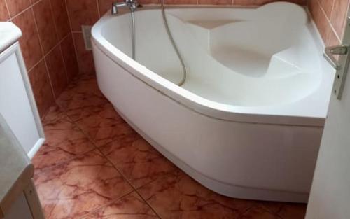 bagno con vasca bianca e pavimento piastrellato di Chambre privée a Sainte-Suzanne