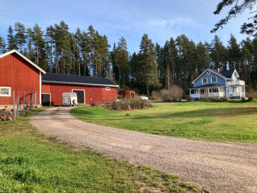 a dirt road next to a red barn and a blue house at Gård Mörbacka Bed & Breakfast in Mörbacka