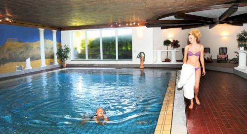 une femme debout à côté d'une piscine dans l'établissement Hotel Traube Lossburg, à Loßburg