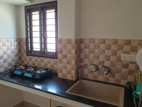 uma cozinha com um fogão e um lavatório em Chippy Apartments 3006B em Chennai