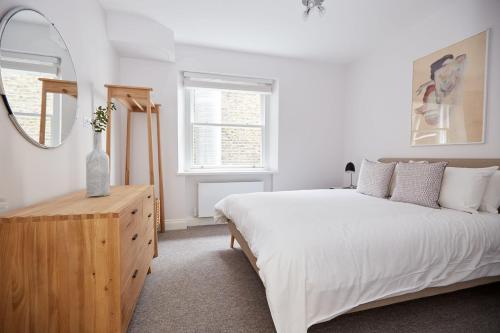 a white bedroom with a large bed and a mirror at 5VH Virginia House, 31 Bloomsbury Way in London