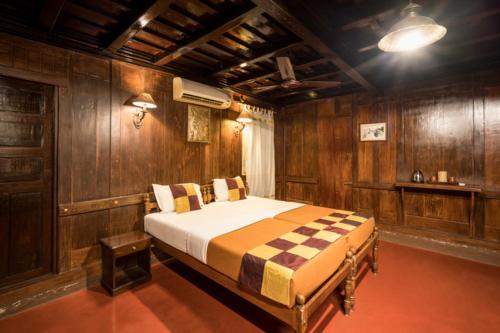 a bedroom with a bed in a room with wooden walls at Emerald Isle in Alleppey