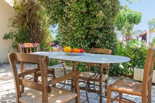 a table with chairs and a bowl of fruit on it at Helen & Theo Studios in Laganas