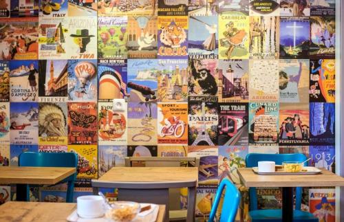 a restaurant with two tables and a wall covered in posters at Eco hôtel Rouen Louviers Val de Reuil in Val de Reuil