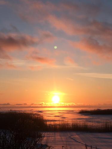 a sunset over the water with the sun in the sky at Pérka kodumajutus in Häädemeeste