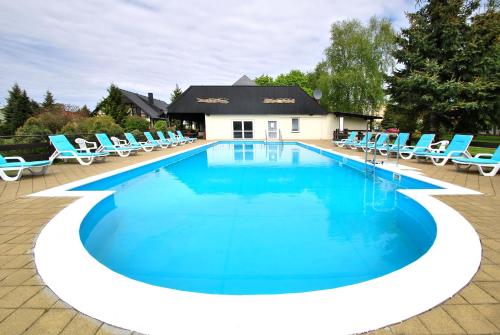 a large swimming pool with blue lounge chairs around it at Lech Resort & Spa in Łeba
