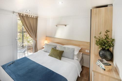 a bedroom with a white bed with a blue blanket at Waterman Beach Village in Supetar