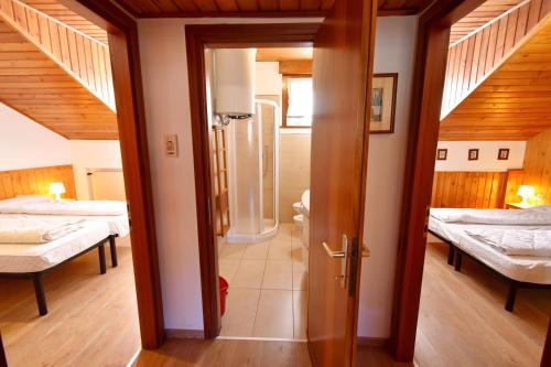 マドンナ・ディ・カンピリオにあるMeneghini Mansarda Centraleのベッド2台付きの部屋、ベッドルームへのドア
