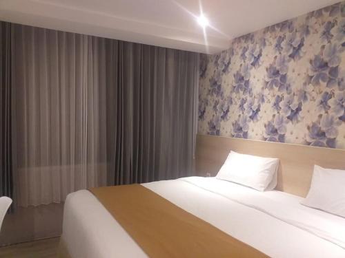a bedroom with a large bed and a floral wall at Hotel Lereng Bromo in Pasuruan