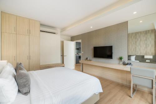 a bedroom with a bed and a desk and a television at Arden Hotel and Residence by At Mind in Pattaya Central