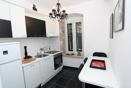 a kitchen with white cabinets and a sink and a table at Apartment Papalić Palace in Split