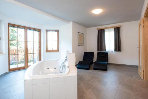 een grote witte badkamer met een bad en 2 stoelen bij Holiday village Koralpe St- Stefan im Lavanttal - OKT07003-FYC in Elsenbrunn