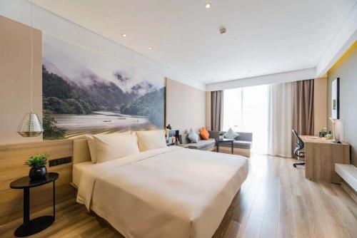 Atour Hotel Hangzhou Future Technology City Haichuang Park في هانغتشو: غرفة الفندق بسرير كبير ومكتب