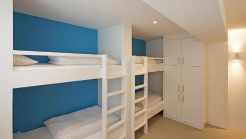 a room with white bunk beds and blue walls at Alte Metzg - Hostel in Appenzell