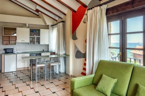 a living room with a green couch and a kitchen at Apartamentos Costa Esmeralda in Suances